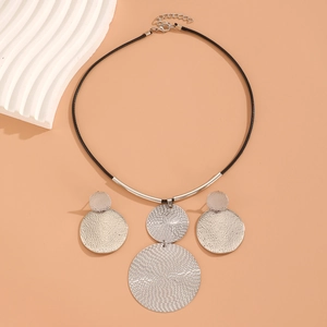 Macro detail of textured silver hammer pattern pendants on black cord necklace set