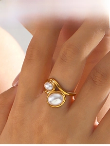 Detailed view of an adjustable golden ring featuring two asymmetrical white pearls