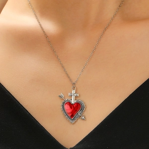 Close-up of heart-shaped red crystal pendant with silver sword and cross on a chain