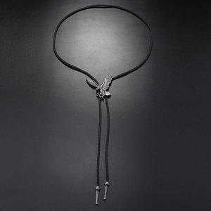 Detailed close-up of eagle-shaped antique silver bolo tie pendant and braided leather cord