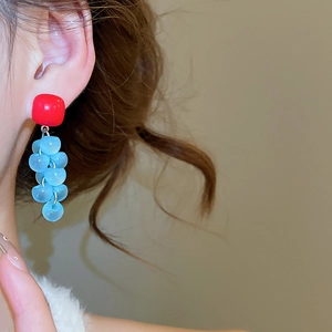 Detail view of square resin stud earrings with light blue grape cluster tassel on model