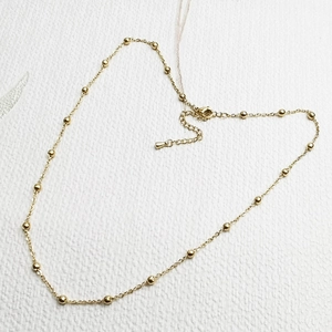 Close-up of golden stainless steel beaded chain necklace with lobster clasp and extender