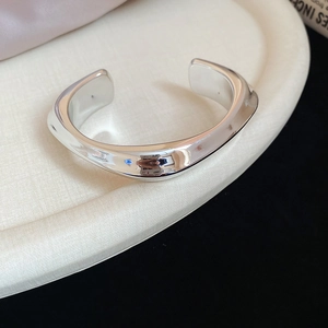 Macro shot of irregular wave-shaped silver cuff bracelet with high-polished finish