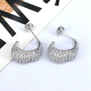 Macro detail of silver C-shaped hoop earrings with sparkling paved zircon stones