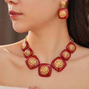 Dettaglio di parure vintage collana e orecchini in smalto rosso con filigrana dorata su modella