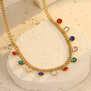 Macro view of colorful crystal pendants on a gold curb chain necklace over white stones