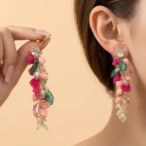 Detail of pink floral tassel earrings with green leaves and faceted crystal beads