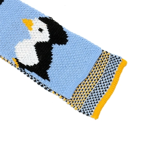 Detail of blue knit scarf with penguin motif and wave-patterned stitching edges