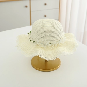 Detail of girls straw sun hat with chiffon flowers and wavy edge on a display stand