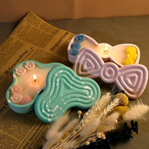 Handmade mint green rippled and pink bow-shaped scented candles with floral accents