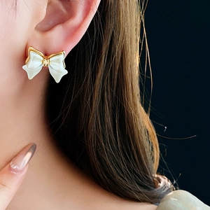 Détail d'une boucle d'oreille nœud plaquée or 14K avec texture perle sur l'oreille