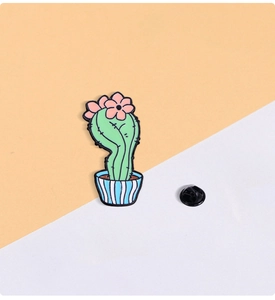 Detail of cartoon cactus enamel pin with pink flower and striped pot featuring a rubber back