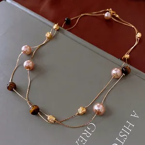 Double-layered gold necklace with faux pearls and tiger eye stones on vintage book