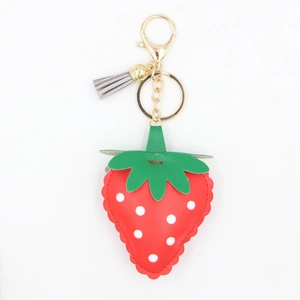 Vue détaillée du porte-clés fraise en cuir PU rouge avec accessoires en métal doré et pompon