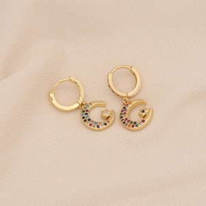 Detailed shot of gold moon and star drop earrings with multi-color zircon stones