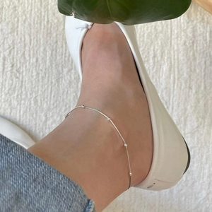 Minimalist 925 sterling silver beaded anklet shown on an ankle with casual shoes