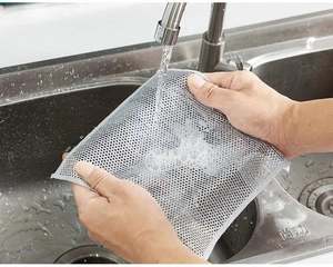 Detail of grey wire dishcloth being rinsed under water for kitchen cleaning