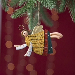 Vintage hand-painted metal angel ornament hanging on a festive Christmas tree branch