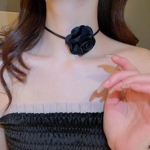 Close-up of a 3D black satin flower choker necklace worn on model's neck for a vintage look