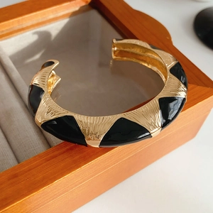 Detail view of a French vintage open bangle featuring gold metal and black enamel finish
