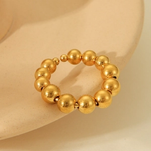 Polished 18K gold-plated beaded open ring displayed on warm beige ceramic dish