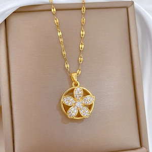 Close-up of a gold rotating five-leaf flower necklace with crystals on a silk display