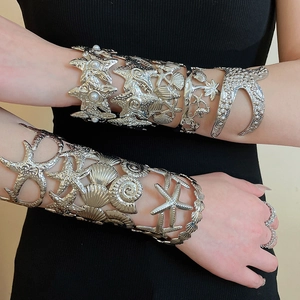 Detailed view of silver metal cuff bracelets with hollow starfish and seashell patterns