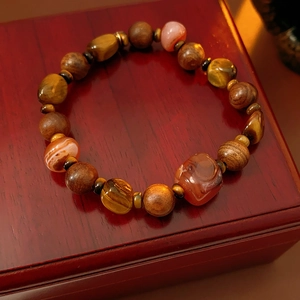 Gros plan d'un bracelet en perles d'oeil de tigre et agate sur un écrin à bijoux en bois