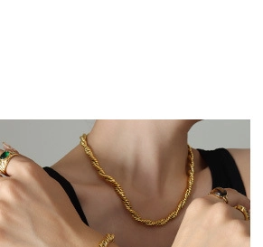 Close-up of gold-plated twisted rope chain necklace and gemstone rings on model