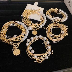 Detail of five gold layered bracelets featuring pearls, chains and a toggle clasp on velvet