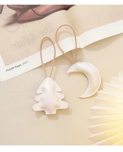 Detail view of pearl white leather Christmas tree and moon ornaments with brown lanyards