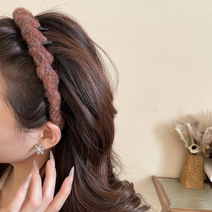 Close-up of red brown knitted wavy headband and sparkling snowflake stud earrings