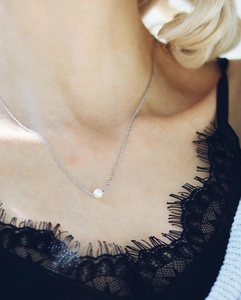 Close-up of a single white pearl pendant on a slim silver stainless steel chain for women