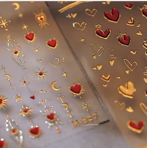 Macro detail of 3D embossed nail stickers featuring red hearts and gold celestial patterns