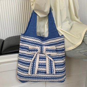 Blue and white striped knit tote bag featuring a large bow and woven texture details