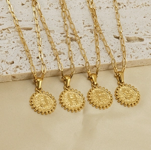 Detail of 18K gold plated paperclip chain with round embossed letter pendants on silk