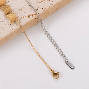 Macro detail of stainless steel lobster clasp and frosted gold butterfly pendant charms