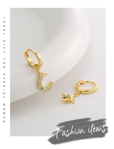 Detail of asymmetric gold star and moon earrings with white and blue zircon inlay