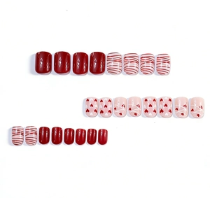 Flat lay of square glossy press-on nails with red heart designs and stripe patterns