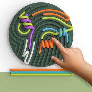 Detailaufnahme einer Kinderhand, die flexible Silikonrohre am sensorischen Aktivitätsbrett bewegt