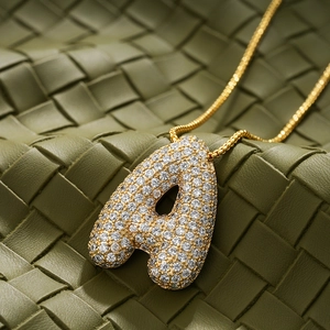 Macro detail of 18K gold plated A-letter pendant with sparkling cubic zirconia inlay