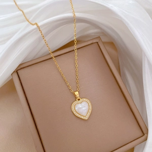Detail of gold heart pendant with mother of pearl and zircons on silk background
