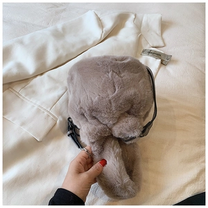Gros plan du sac seau gris en fausse fourrure pelucheuse sur un blazer blanc