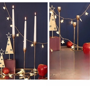 Three gold candle holders in varying heights with round bases on dark blue background