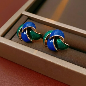 Macro detail of vintage-style enamel earrings with blue and green glossy finish in a gift box