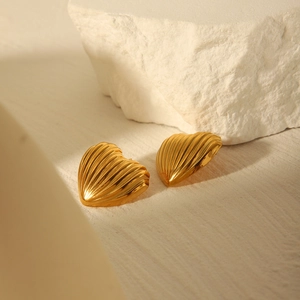Macro detail of 18k gold heart stud earrings with radial ripple texture on white stones