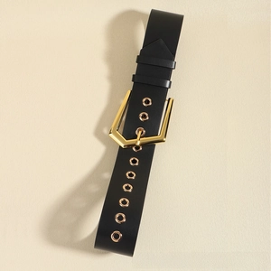 Detail of black elastic belt with golden shield buckle and decorative metal eyelets