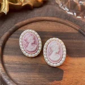 Detailed macro view of vintage pink cameo portrait earrings with small pearl borders