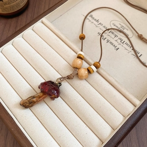 Detail of red mushroom pendant necklace with wooden beads in a velvet jewelry box