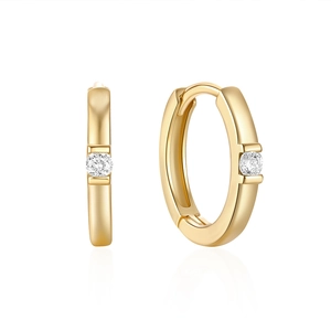 Close-up of a 18K gold hoop earring featuring a single round-cut sparkling diamond